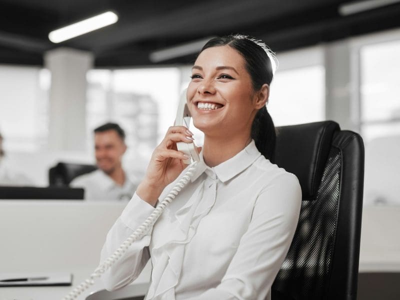 Delighted secretary speaking on telephone with client